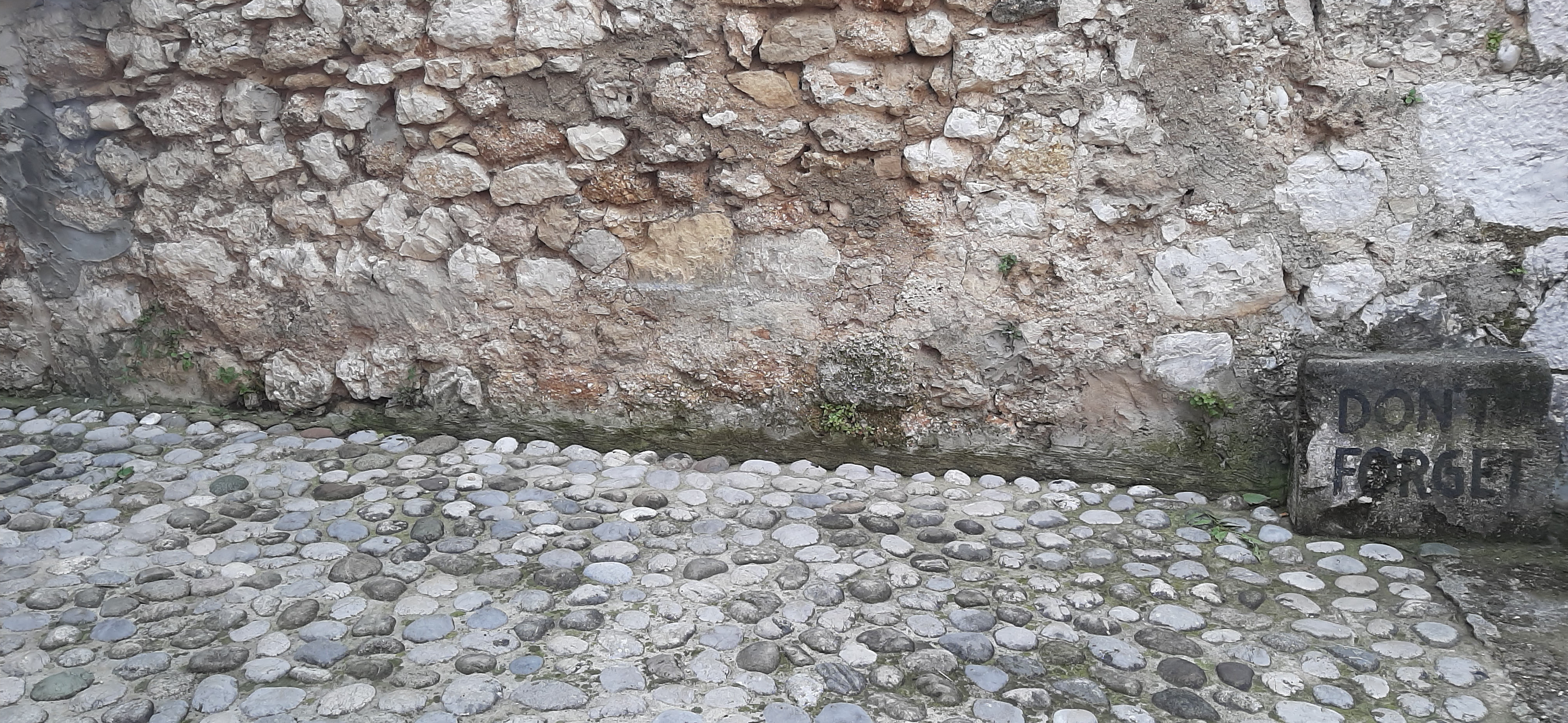 a rocky wall and floor, on the right is a sign with faded-out text saying: don't forget